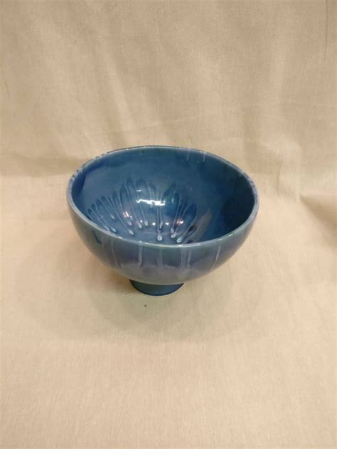 A Blue Bowl Sitting On Top Of A White Cloth Covered Table Next To A Wall