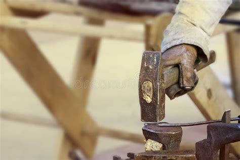 Blacksmith At Work Hammer In Hand Hitting The Anvil Stock Image