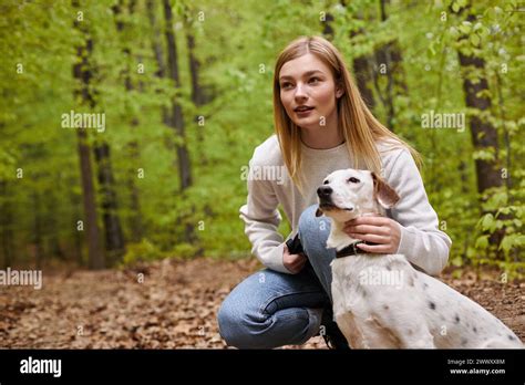 Blonde Hiker Girl Interacting With Her Pet Looking At Direction While Hiking Rest With Forest