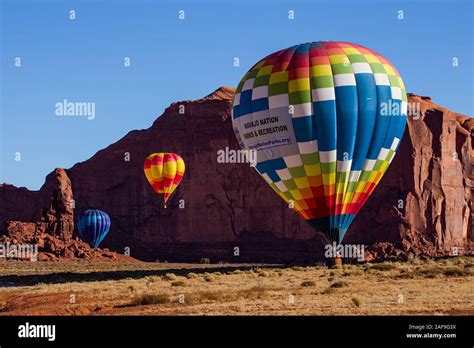 Three Hot Air Balloons Land In Front Of Rain God Mesa In The Monument