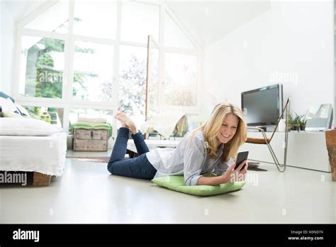 Mature Woman Lying On Floor Using Smartphone Stock Photo Alamy