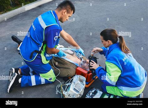 Team Of Paramedics Performing CPR With Mobile Defibrillator And