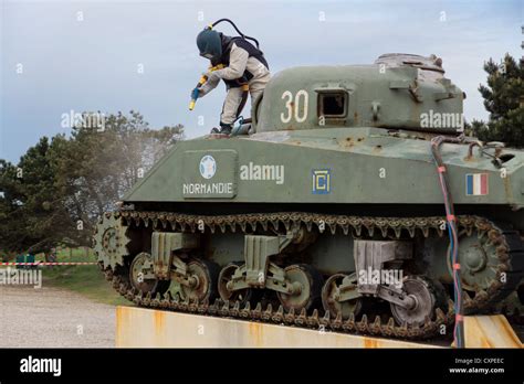 "Utah Beach", Normandy. A man sand-cleans a wwii era tank of the French ...