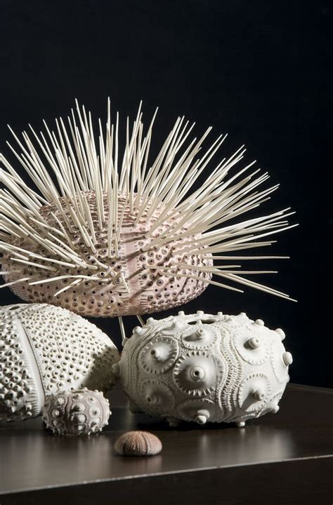 Two White Sculptures Sitting On Top Of A Table Next To Shells And Seashells