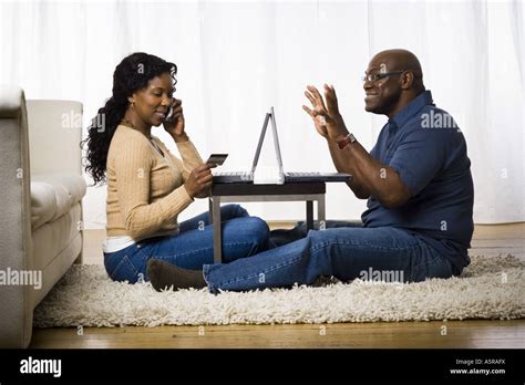 Profile Of A Mature Woman Talking On A Mobile Phone With A Man Sitting In Front Of Her Stock