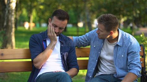 Man Comforting Sad Male Friend Sitting On Bench At Park Life Problems