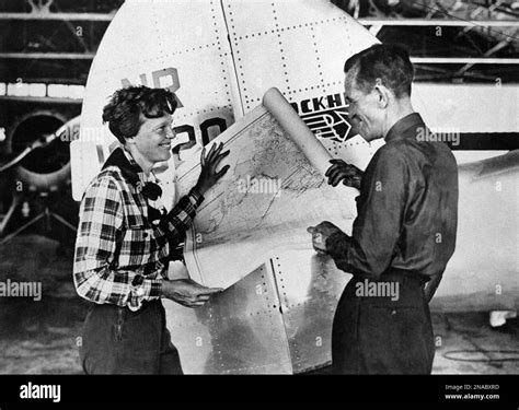 Aviation pioneer Amelia Earhart and navigator Fred Noonan pose with map of the Pacific showing ...