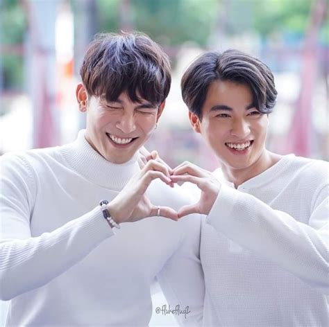 two young men making a heart shape with their hands while standing next ...