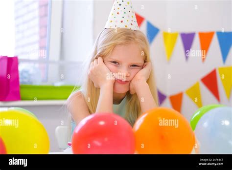 Jeune fille blonde blonde caucasienne avec un visage ennuyeux près du gâteau arc en ciel d