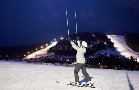 Unrecognizable Female Skier With Hands Up With Ski Poles Back View