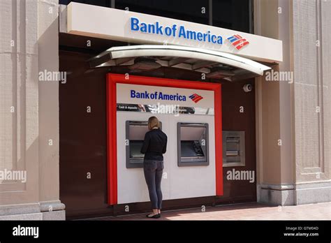 A woman stands at a Bank of America ATM machine, Bank of America branch ...