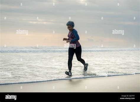 Fit And Attractive Mature Woman With Grey Hair Doing Beach Workout On Her S Running On The