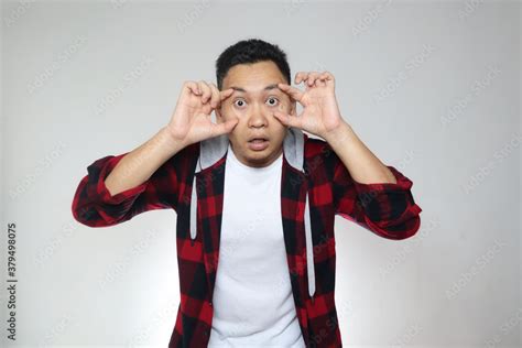 Portrait Of Funny Young Asian Man Widening His Eyes With Fingers