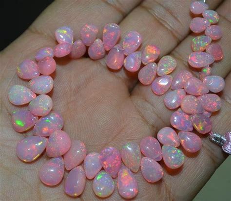 A Hand Holding A Pink And White Heart Shaped Necklace With Lots Of