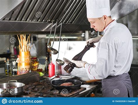 Cocinero En Cocina Del Restaurante En La Estufa Con La Cacerola