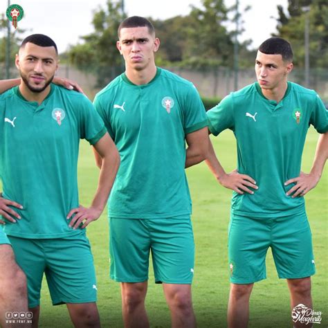 Three Soccer Players In Green Uniforms Standing On The Field With Their