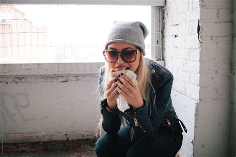 Female Wearing Black Eating Burger In Abandoned Building By Stocksy Contributor Jesse Morrow