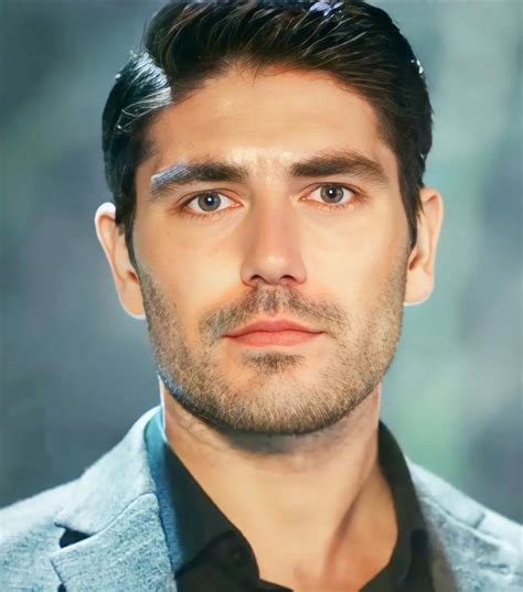 A Close Up Of A Person Wearing A Suit And Tie With His Hair Pulled Back