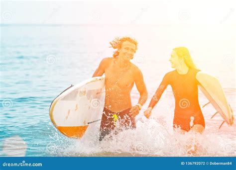 Surfers At The Beach Smiling Couple Of Surfers Walking On The Beach