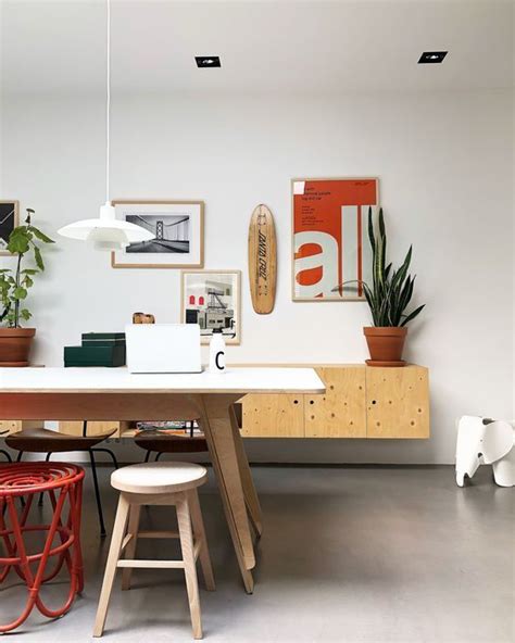 A Table With Two Stools In Front Of It And Some Pictures On The Wall