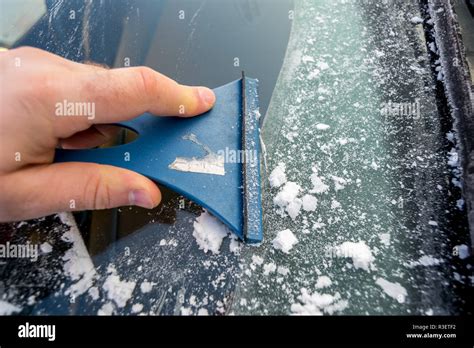 Man Outdoor Cleaning Snow On His Car Windshield View From Outside Of