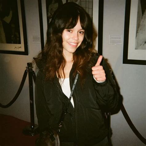 A Woman Giving The Thumbs Up Sign In Front Of Pictures On Display At An