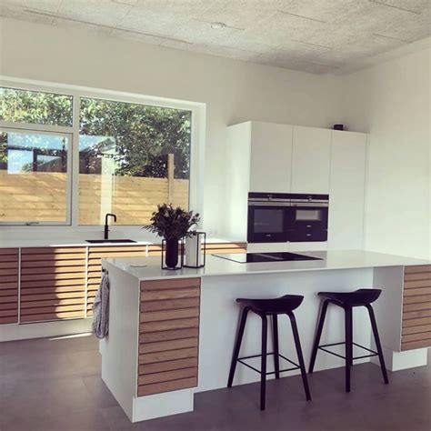 A Kitchen With Two Bar Stools Next To An Oven And Counter Top In Front