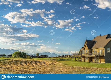 Scenic Landscape With Homes On A Grassy Terrain Under Blue Sky And