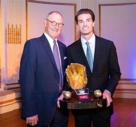 Two Men Standing Next To Each Other Holding Trophies