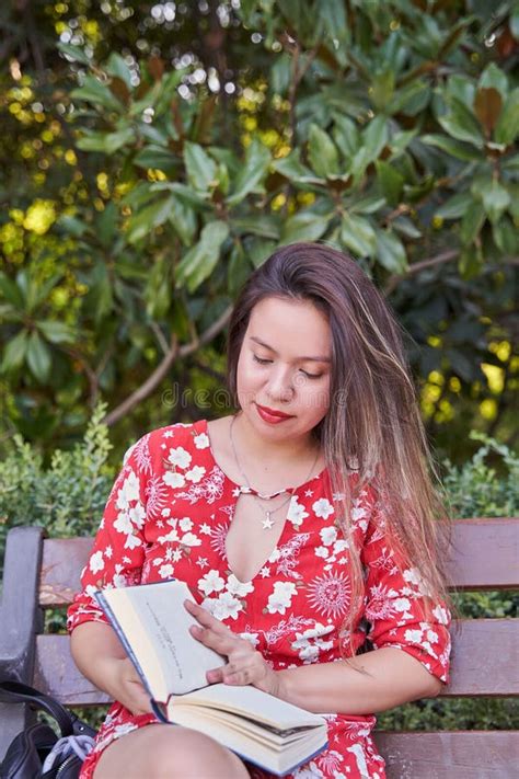 Foto Vertical De Uma Mulher Latina Lendo Um Livro Num Parque Sentado Num Banco Foto De Stock