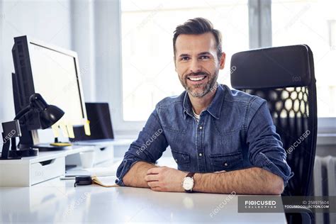 Portrait Of Smiling Man Sitting At Desk In Office Computer Screen