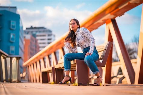 Una Chica Latina Morena En La Ciudad Al Atardecer En Un Puente Naranja Posando Del Sentado