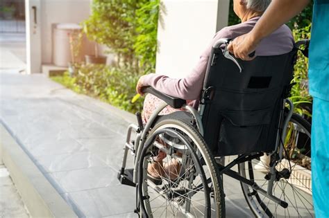 Cuidador Ayuda Y Cuida A Una Anciana Asi Tica Sentada En Silla De