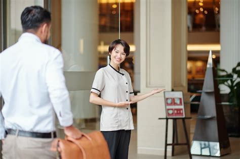 Premium Photo | Smiling hospitable consierge welcoming guest at doors ...