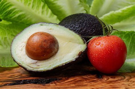 Fresh Organic Avocado Cut In Half And Organic Red Tomatoes On The Vine