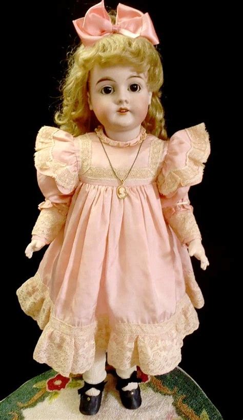 An Old Doll With Blonde Hair Wearing A Pink Dress And Black Shoes On