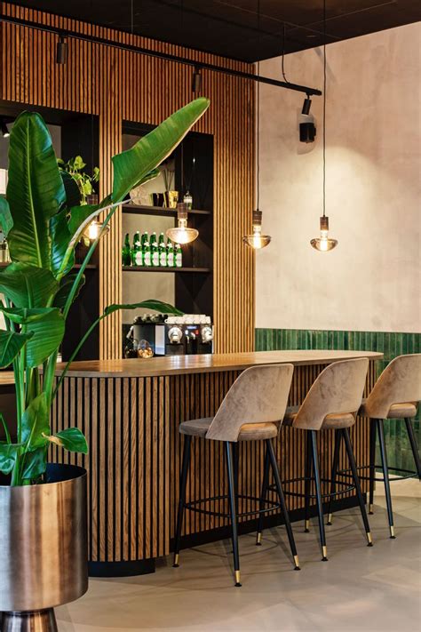 A Bar With Stools Next To A Plant In A Pot On The Floor And Lights