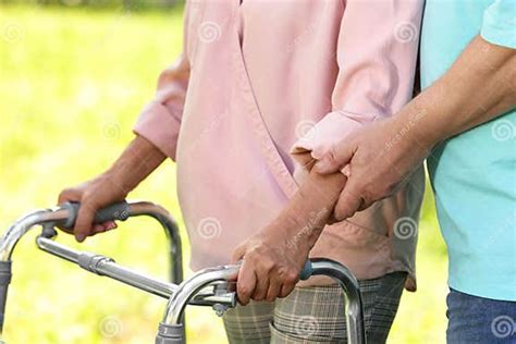 Elderly Man Helping His Wife With Walking Frame Outdoors Stock Image