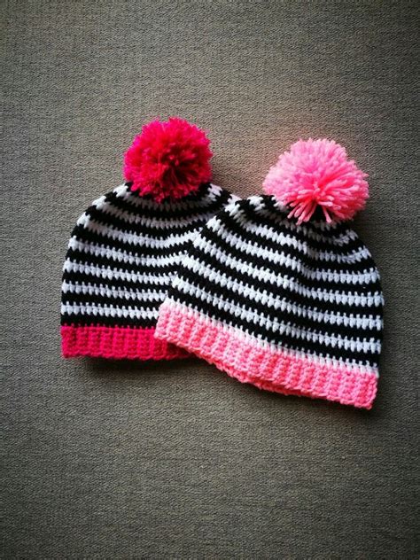 A Black And White Striped Knitted Hat With Pink Pom Pom On Top