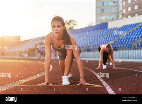 Women Sprinters At Starting Position Ready For Race On Racetrack Stock