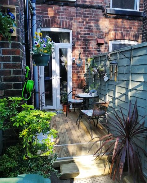 An Outdoor Patio With Chairs Table And Potted Plants On The Side Of It