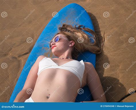 Jovencita Rubia Linda Mujer Con Un Bikini Blanco Y Gafas De Sol Tendidas En Una Tabla De Surf