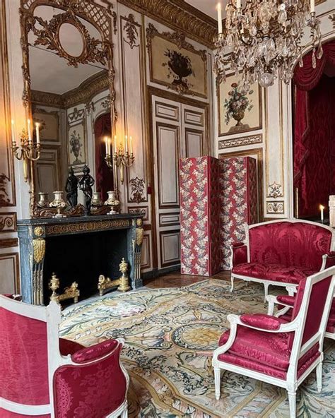 An Ornately Decorated Living Room With Chandelier And Red Chairs