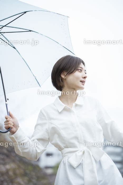 雨の中傘をさして歩く白いワンピースを着た若い女性の写真素材 164115749 イメージマート