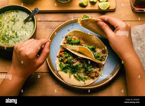 Woman S Hand Holding A Taco Of Marinated Meat Plate With Tacos Sauce