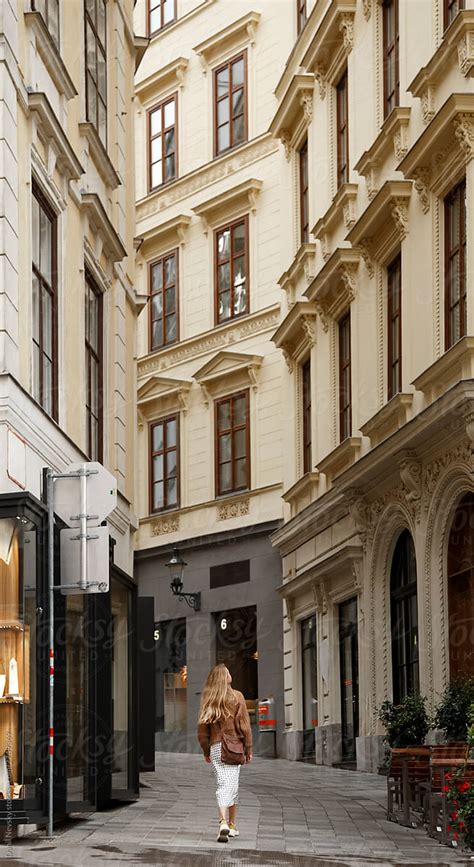 Woman Going Along Street Between Old Buildings With Beautiful Baroque Architecture By Stocksy