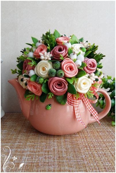 A Pink Tea Pot Filled With Flowers On Top Of A Table