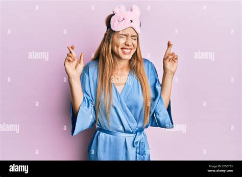 Beautiful Young Blonde Woman Wearing Sleep Mask And Pajama Gesturing