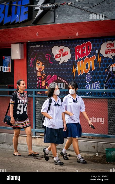 Young Thai School Girls Make Their Way Along The Busy Road Of Soi