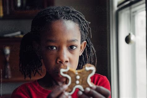 "Black Girl Eating A Gingerbread Man Cookie" by Stocksy Contributor "Gabi Bucataru" - Stocksy